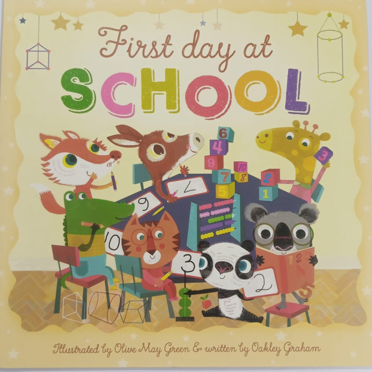Cover of a children book titled 'First day at SCHOOL', featuring illustrations of various animals and school-related items.