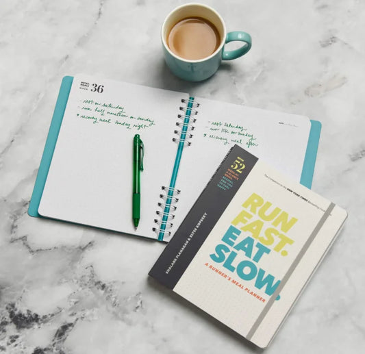 Open planner with a cup of coffee and a pen on a marble surface
